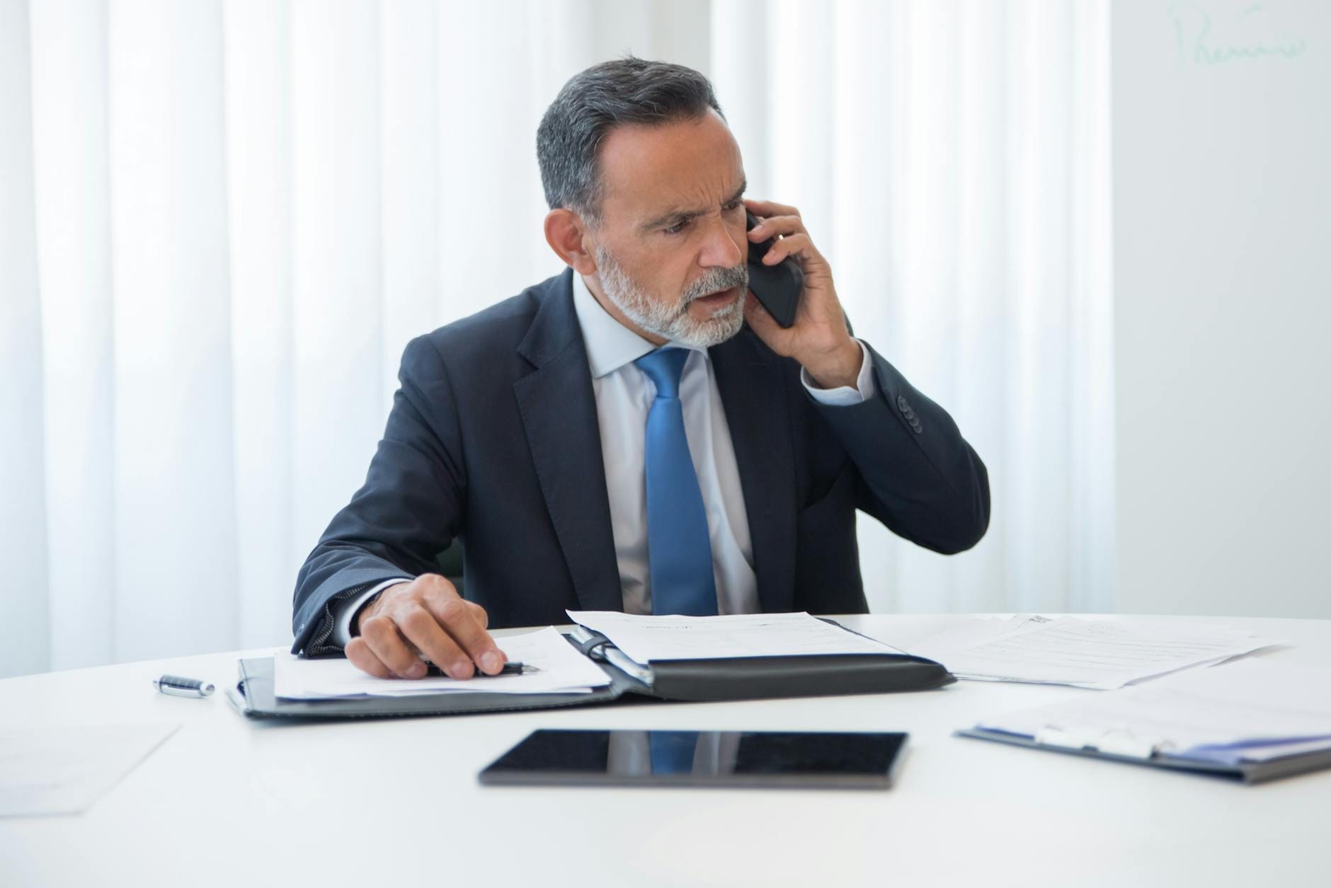 Biznesmen w garniturze rozmawia przez telefon przy biurku w biurze Biznesmen w garniturze rozmawia przez telefon przy biurku w biurze