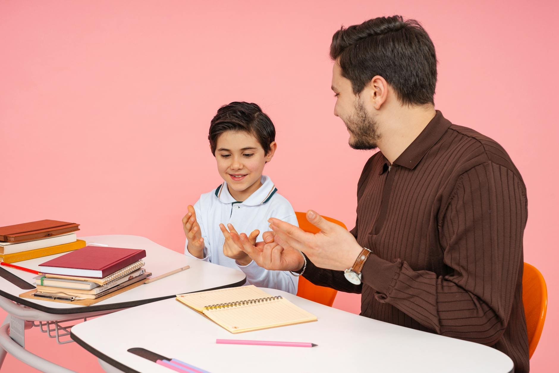 Nauczyciel rozmawia z uśmiechniętym uczniem podczas zajęć w klasie